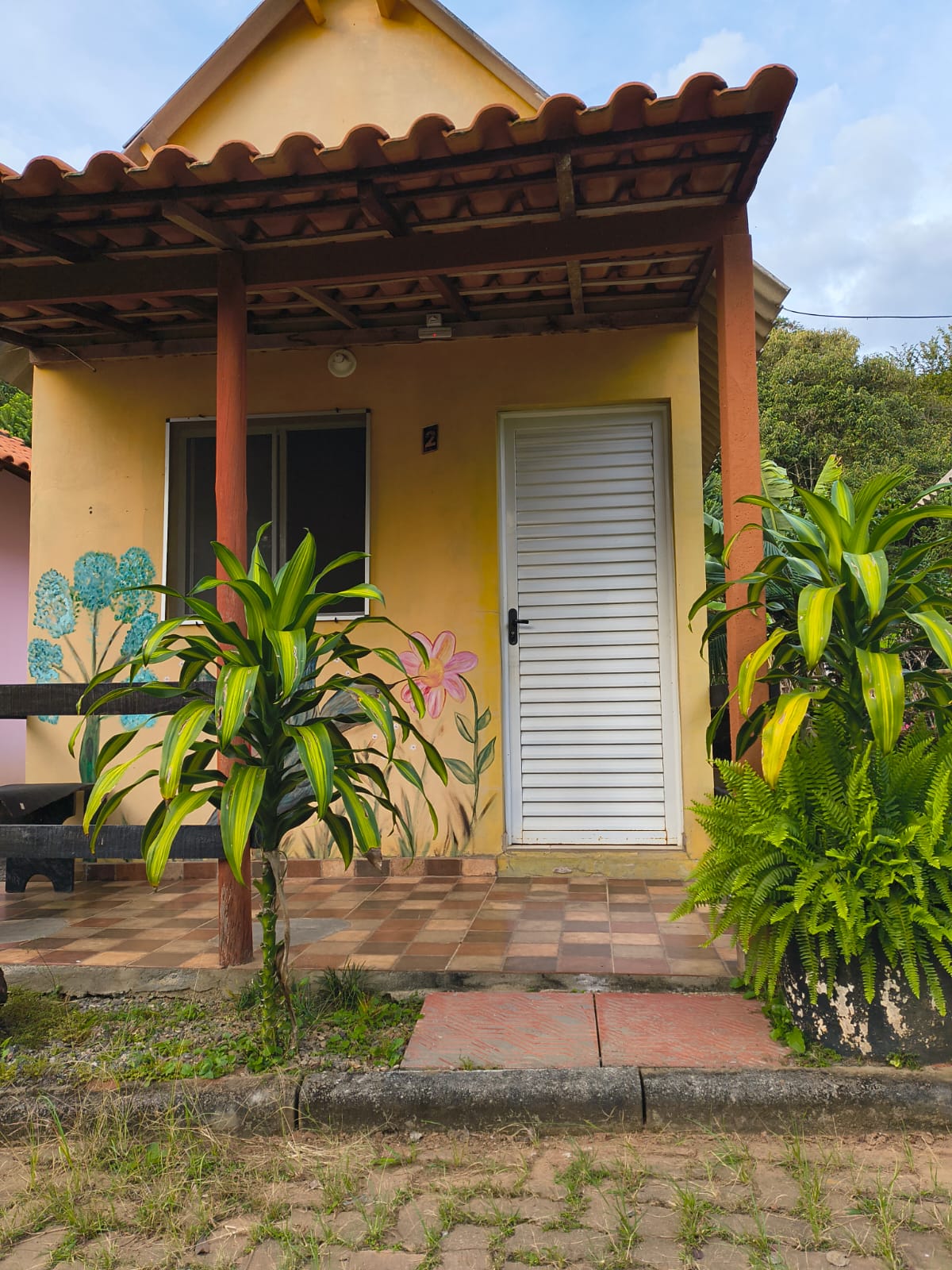 Chalé amarelo com flores pintadas